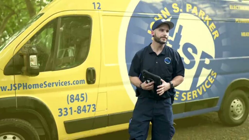 A Man In Uniform Stands In Front Of A Yellow Van With “John S. Parker Home Services” And Contact Information Printed On The Side.